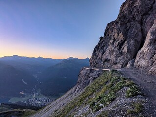 A winding dirt road rising steeply along the side of a mountain