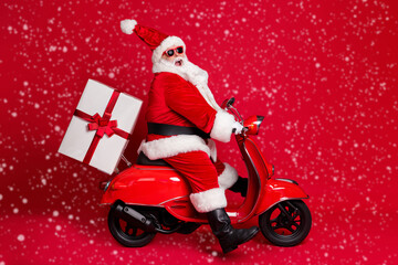 Full length profile photo of retired grandpa white beard ride vintage motorbike high speed late deliver present wear santa x-mas costume coat sunglass cap isolated red color background