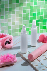 vibrant bathroom countertop hosts two sleek spray bottles alongside a fluffy pink headband, yoga mat, and grooming tools. The tranquil green mosaic tile backdrop enhances the serene setting, while the