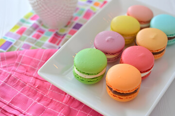 Brightly colored macarons neatly arranged on white plate create delightful and vibrant display. These sweet treats are perfect for any celebration or gathering
