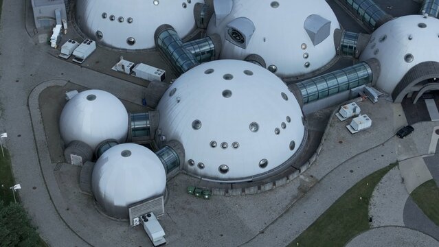 Drone View of Domes Connected by Glass Tunnels Resembling an Alien Research Base An intriguing drone view of interconnected domes linked by sleek glass tunnels, resembling a futuristic base designed f