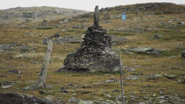 A dark weather-worn stone cairn in the bleak autumn tundra. Parallax shot.