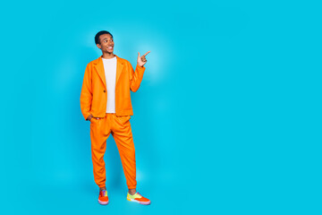 Photo of attractive guy standing point finger empty space wear trend orange suit isolated cyan...