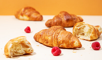 Fresh croissants with raspberry on yellow and orange background. Creative  trendy layout and healthy food