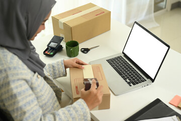 Smiling small business owner packaging a parcel for delivery to customers. E-commerce concept