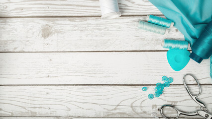 Tailoring concept. Accessories for sewing and needlework. Scissor and blue cotton fabric. Top view.