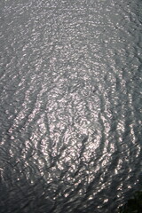 Monochrome ripples of water reflecting sunlight, creating a mesmerizing texture and abstract pattern in nature.