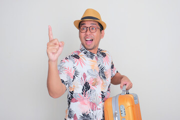 A man carry pointing forward with excited expression while carrying a luggage