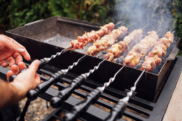 Close-up of male hands holding skewers with meat