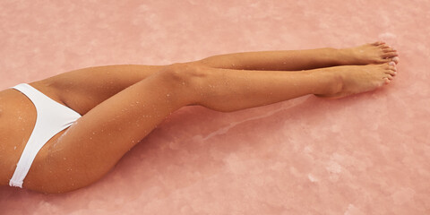 Close-Up of Woman's Legs in White Bikini on Pink Salt Surface