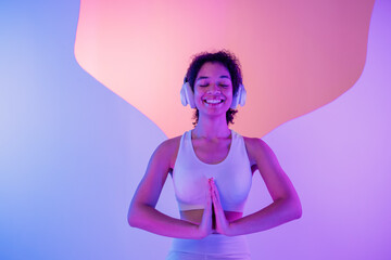 A young African in white sportswear sits in a meditation pose on round platform