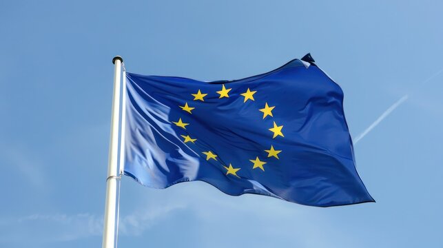 A European Union flag waving in the wind with a clear blue sky in the background - Powered by Adobe