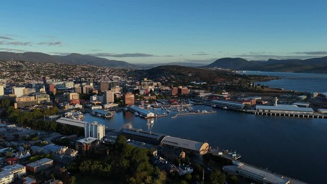Aerial establishing shot of Hobart City with pier and port at golden sunset, Tasmania. Port with cityscape in Australia. Wide shot.