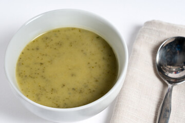 Homemade courgette soup with French Boursin cheese serbed in bowl on white background.
