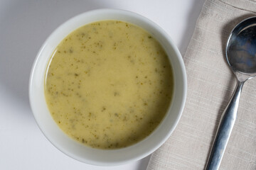 Courgette soup with boursen cheese serbed in bowl on white background.. Top view.