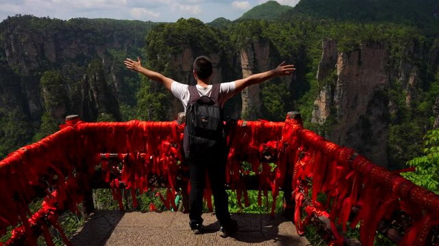 Excited photographer extends his arms in a V sign while admiring the landscape of Yuanjiajie, China