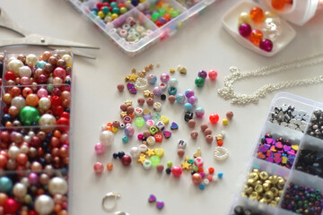 Colorful beads, letter beads, threads and other jewelry making supplies on white background. Making friendship bracelets concept. Selective focus.