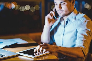 Business App. Serious Businessman Using Tablet Computer Sitting In Modern Office At Night. Selective Focus