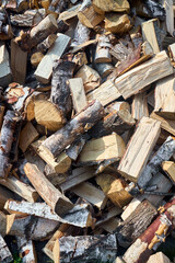 Stack of birch firewood with hand chopping block. Chopped firewood for winter. Lot of firewood - harvesting wood for heating the house. Vertical photo. Chopped firewood background and texture.