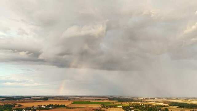 Time lapse The Rainbow Over the Green Field After Storm With Rain, During Outumn, Aerial View Under Heavy Clouds Before Thunderstorm. Agriculture Landscape Many Crop Fields. Aerial 4k Shot
