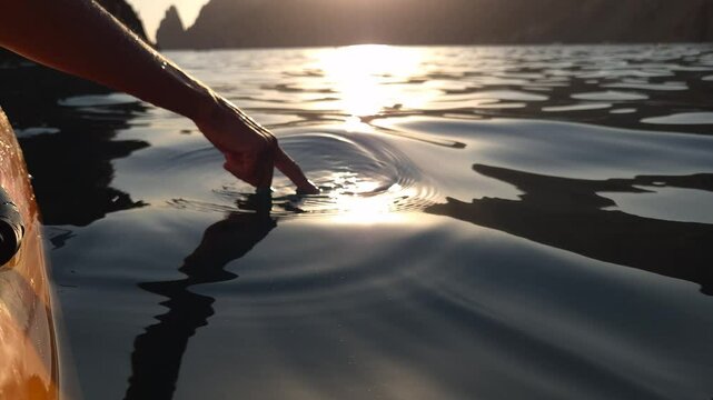 Sunset, Kayaking, Ocean - A close-up view of a kayaker's paddle dipped into the water as the sun sets over the ocean, creating a golden reflection.