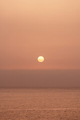 A serene sunset over the calm ocean viewed from a coastal cliff in the evening