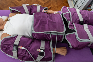 Woman undergoing pressotherapy, using a specialized suit with controlled air pressure to enhance...