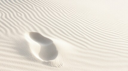 Obraz premium A solitary footprint in a smooth, sandy landscape with gentle ripples.
