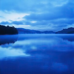 Fototapeta premium A serene blue lake reflecting clouds and mountains, creating a tranquil atmosphere in nature's untouched beauty.