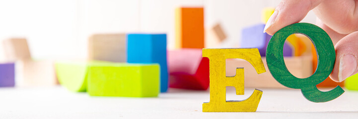 Kids EQ, child emotional quotient concept with wooden cubes children toys on background, wooden cubes kids toys on background, letters text lettering EQ in the foreground