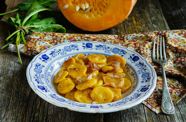 rustic and delicious plate of handmade pumpkin gnocchi topped with crispy greaves, served on an elegant blue and white porcelain dish.