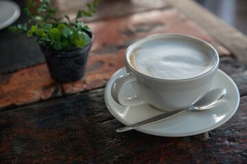 White cup of cappuccino coffee on wooden tabletop, close up. Copy space.