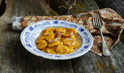 rustic and delicious plate of handmade pumpkin gnocchi topped with crispy greaves, served on an...