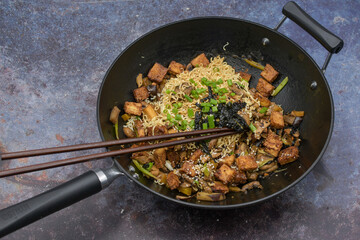 Vegan stir fry in wok  consisting of tofu and vegetables, noodles