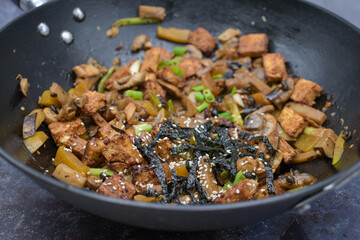 Crispy tofu stir fried in wok along with  mushrooms and  eggplant