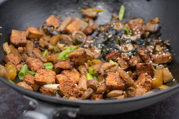 Crispy tofu stir fried in wok along with  mushrooms and  eggplant