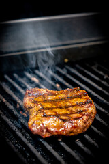 Beef steak on the grill with smoke and flames