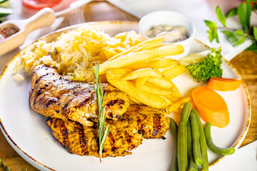Tender grilled porterhouse or t-bone steak served with crisp golden French fries and fresh green...