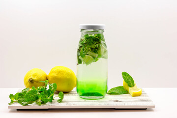 Green Apple Mojito Soda with Lime and Mint served in bottle isolated on wooden board side view of cold beverage on white background