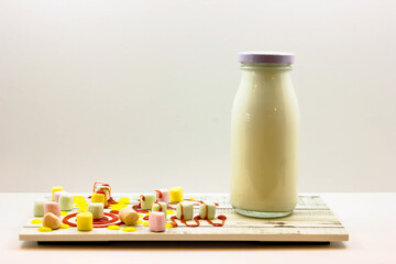 Refreshing Banana Smoothie or Milkshake with Marshmallows and Drizzle served in bottle isolated on wooden board side view of cold beverage on white background