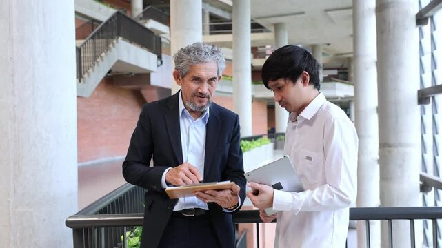 Asian senior professor is giving advice to the college student on the research thesis while sitting in the university faculty for education, academic and business
