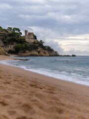 the sea waves at the sandy shore, beating against the rocks. A sailboat at sea. A pigeon sky over a blue sea.