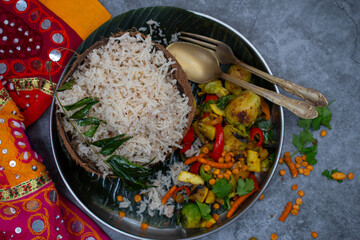 Vegan coconut rice served in coconut shell bowl. Vegetable curry on banana leaf. South Indian vegan sustainable servingware, environmentally frendly.