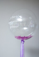a transparent bubble balloon with purple feathers the inscription: "Happy birthday, daughter!"