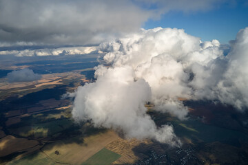 Aerial view at high altitude of earth covered with puffy cumulus clouds forming before rainstorm