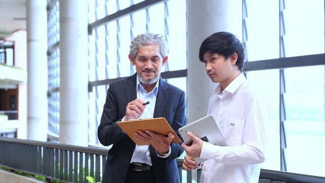 Asian senior professor is giving advice to the college student on the research thesis while sitting in the university faculty for education, academic and business
