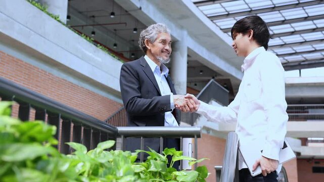 Senior asian executive manager is handshaking with the new trainee employee during probation to pass on knowledge and experience for new generation business inspiration, education and academic