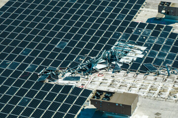 Aerial view of damaged by hurricane wind photovoltaic solar panels mounted on industrial building...