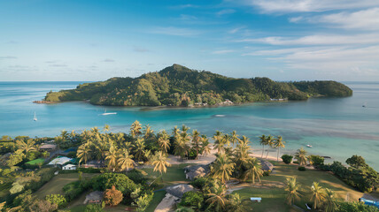 An aerial view of a tropical island with palm trees and sandy beaches, surrounded by a turquoise sea