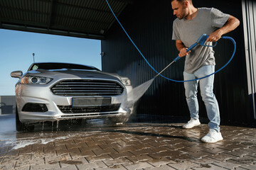 Standing and washing the automobile. Man is with his car outdoors